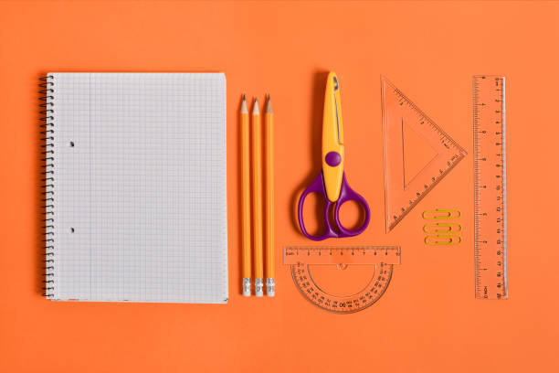 istock Blank notebook with school and office supplies on orange background top view. 1263340310