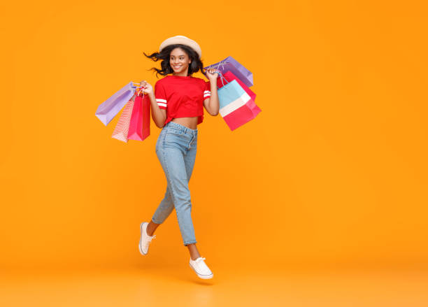 conceito de compras e vendas de menina feliz com pacotes em fundo amarelo - shopping shopping bag shopping mall retail - fotografias e filmes do acervo