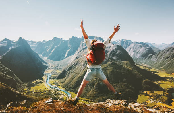 幸せな男の旅行者は、ノルウェーの山の成功と楽しい幸福感の感情で屋外でアクティブな夏休み、バックパックトラベルライフスタイルアドベンチャーコンセプトでジャンプ - outdoors exercising climbing motivation ストックフォトと画像