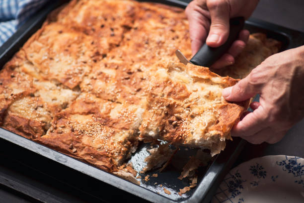 istock Man hands cutting fresh baked homemade cheese pie with a roller knife 1263342768