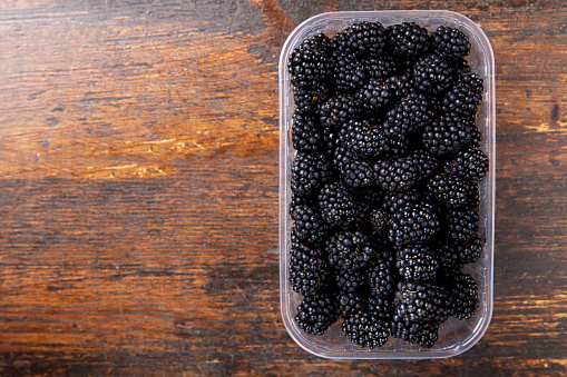ripe blackberry in a box on a wooden background. place for text