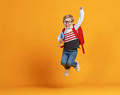 Happy school boy jumping with raised arm