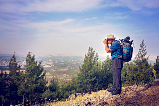 Traveler hiker man with backpack hiking on top of mountains taking photos
