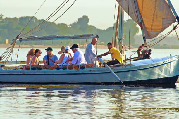 Unidentified people on an excursion on the Nile River in felucca traditional wooden sailing boat . Young Egyptian leads the boat Luxor, Egypt - October 16, 2011: Unidentified people on an excursion on the Nile River in felucca traditional wooden sailing boat . Young Egyptian leads the boat nile delta photos stock pictures, royalty-free photos & images