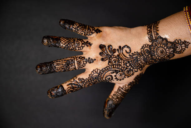 istock Human hand decorated with henna tattoo on black background 1263350718