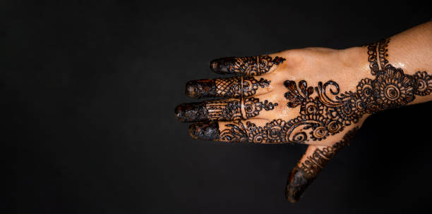 istock Human hand decorated with henna tattoo on black background 1263350728