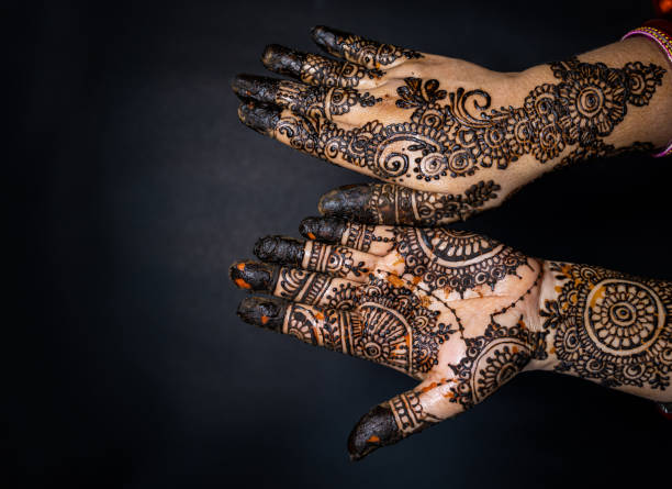 istock Human hand decorated with henna tattoo on black background 1263350754