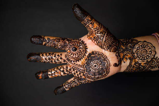 istock Human hand decorated with henna tattoo on black background 1263350762