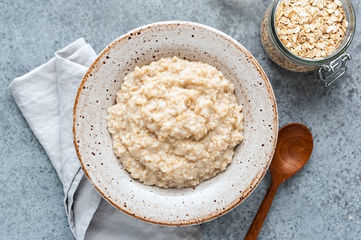 Plain oatmeal porridge in bowl. Healthy vegan vegetarian breakfast food, whole grain porridge oats