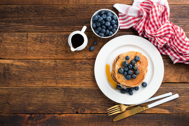 Pancakes with blueberries and maple syrup on wooden table background