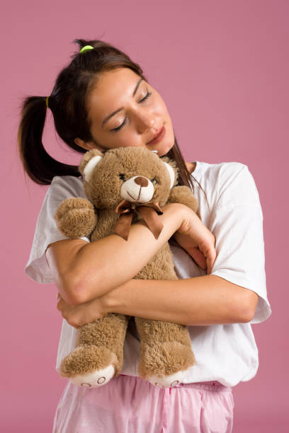 istock Young Beautiful Woman Hugging Soft Toy Bear On Pink Background 1263353746