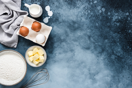 Ingredients for baking on a blue navy background with copy space. Flour sugar butter and milk for cooking dessert