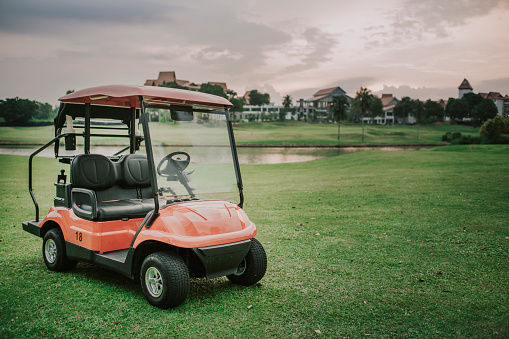 a red golf cart in the golf course during sunset