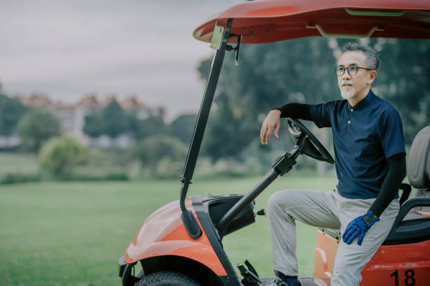 um golfista chinês asiático sentado em um carrinho de golfe após o jogo de golfe - golf course golf people sitting - fotografias e filmes do acervo