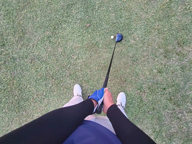 Young female golfer lying on green holding ball in front of eye view from above