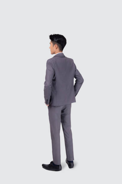 白い背景に自信を持って孤立したポケットにスーツの手を持つ若いアジアのビジネスマンの背面図は、ビジネスマンの背中は、成功、完全な長さで考えているマネージャーやエグゼクティブ� - asian ethnicity suit business men ストックフォトと画像