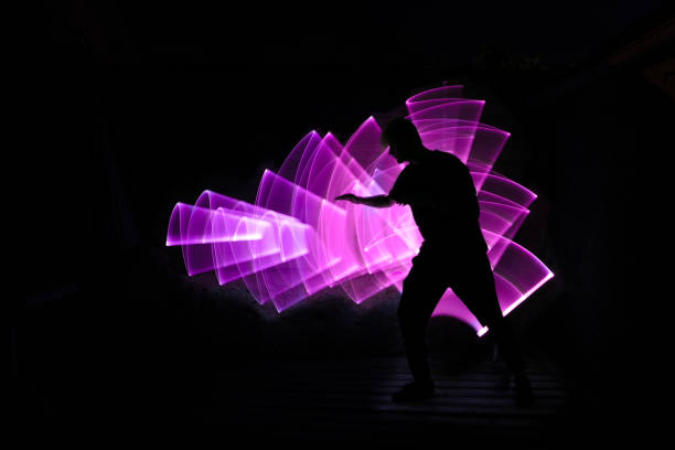 Lightpainting scene. Silhouette of a man in profile with outstretched arm. Abstract light saber shape in background. lightpainting stock pictures, royalty-free photos & images