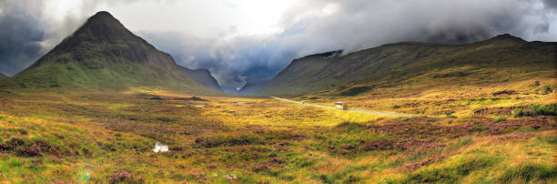 Road through mountains in highlands valley of Scotland, bus traveling asphalt , panoramic view stock photo