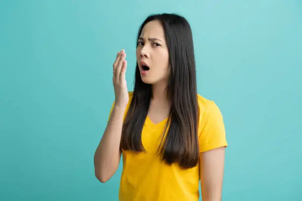 Photo of Asian woman, she is testing her bad breath.