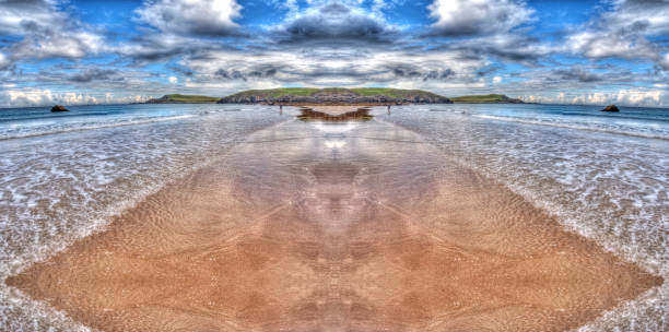 two men look at each other, on the opposite sides of the seashore on the golden beach. But are they really looking at each other?Speculare surreal image stock photo