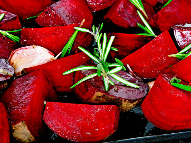 Juicy beet slices before baking. Fresh rosemary. Roast beetroot. Preparation of baked beets. Quarter beets with rosemary, garlic and spices, sprinkled with oil before baking.