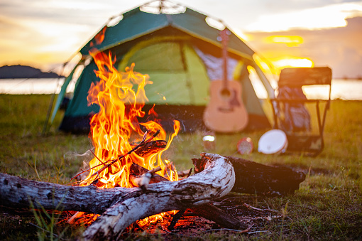 Camping bonfire surrounded by team of asian climbers hiker, they are playing music together in the forest path autumn season. Hiking, hiker, team, forest, camping , activity concept.
