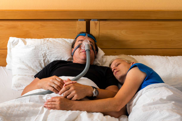 istock man using cpap mask because of obstructive sleep apnea, his wife is beside 1263374906
