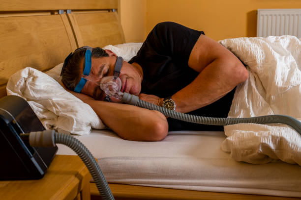 man sleeping with cpap mask because of obstructive sleep apnea man using cpap machine to stop choking and snoring from obstructive sleep apnea sleep apnea photos stock pictures, royalty-free photos & images