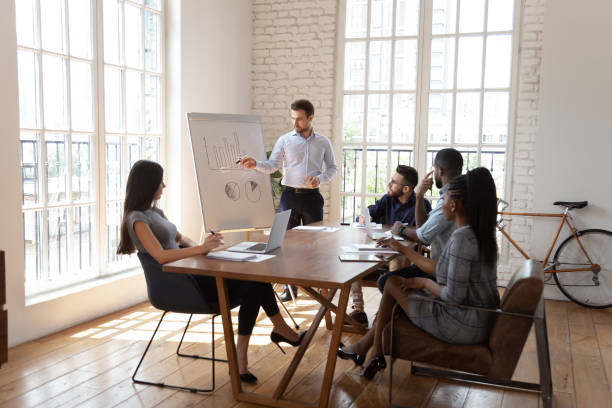 istock Male coach make whiteboard office presentation to diverse employees 1263380378