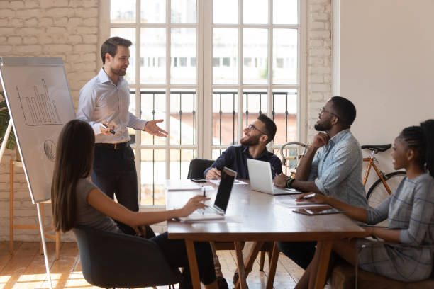 istock Smiling male presenter talk with excited multiethnic workers at briefing 1263380496
