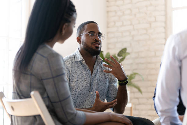 homem afro-americano fala em sessão de terapia de grupo - language therapy - fotografias e filmes do acervo