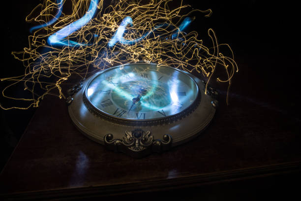 istock Time concept. Big vintage round clock on wooden table with abstract light. 1263381139