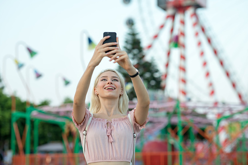 Beautiful girl taking photos at the amusement park