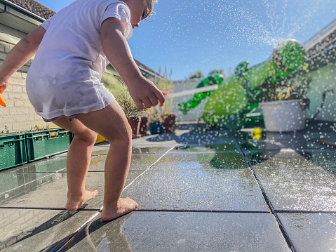 Toddler boy having water fun on a warm summer day
