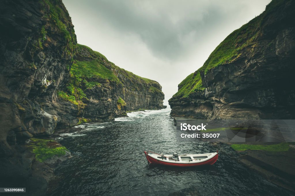 natural harbor in gjógv, faroe islands boot resting in traditional natural cliff harbor in gjogv village, located on the northeast tip of the island of eysturoy, in the faroe islands and 63 km north by road from the capital of tórshavn. Faroe Islands Stock Photo