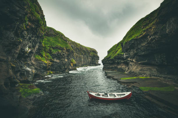 natural harbor in gjógv, faroe islands boot resting in traditional natural cliff harbor in gjogv village, located on the northeast tip of the island of eysturoy, in the faroe islands and 63 km north by road from the capital of tórshavn. eysturoy photos stock pictures, royalty-free photos & images