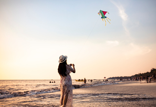 Little girl raises a kite in a sky where some other kites are also flying