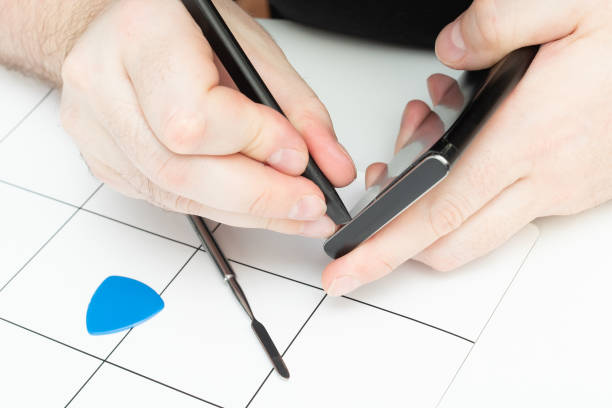 A specialist opens the lid of a smartphone using special tools
