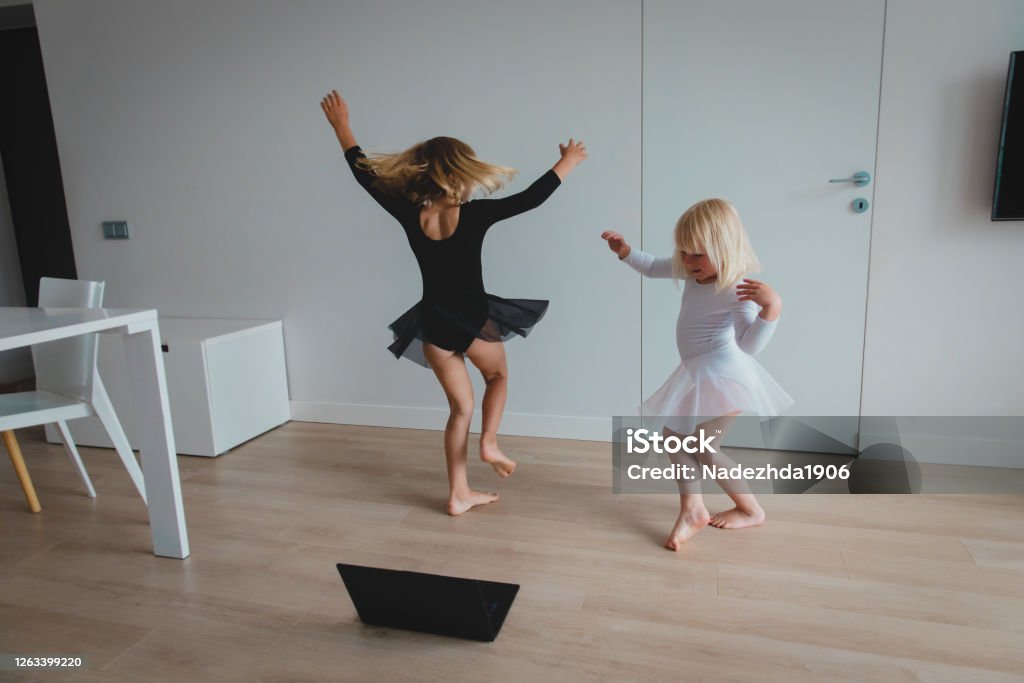 Ballet or gymnastics lesson online. Remote learning for kids. Ballet or gymnastics lesson online. Remote learning for kids. Little girls enjoy dancing during video lesson. Dancing Stock Photo