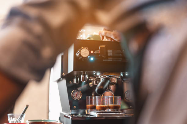 istock Close-up coffee maker that is professionally extracting coffee by barista with a deep white glass in the evening sun light. coffee, extraction, deep, machine, make, barista concept. 1263401118