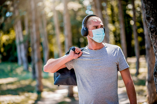 Portrait of young man in sportswear with a medical mask on his face going on training.