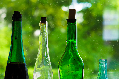 Vintage bottles on the background of a dirty window and greenery outside the window