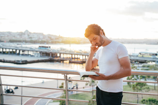 istock Handsome man is reading book with facial mask 1263408945