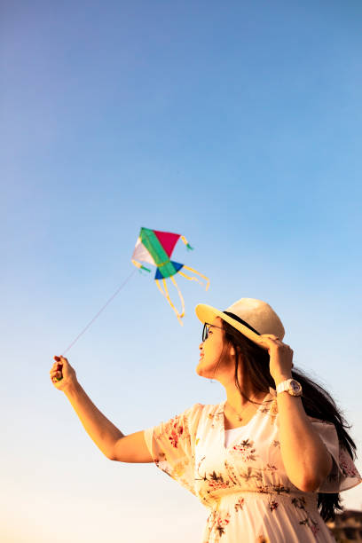 istock asian woman playing kite on the beach 1263410962