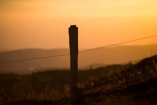 Closeup of wooden fence silhouette at the top of themountain on sunset background