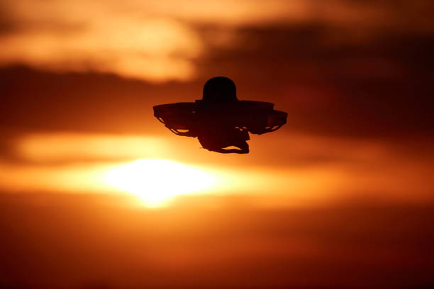 istock Small blue drone also multicopter as a silhouette, orange evening sky with a slightly burned out sun. Germany. 1263412560