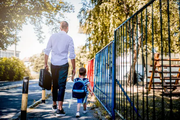 Photo of Business father and son going to kindergarten.