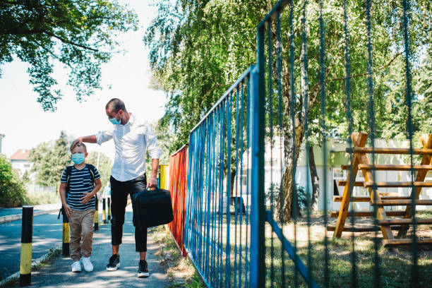 pai solteiro indo trabalhar e levando filho para a escola durante a epidêmia - regresso às aulas - fotografias e filmes do acervo