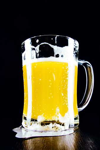 Lager unfiltered beer mug with foam on a dark background