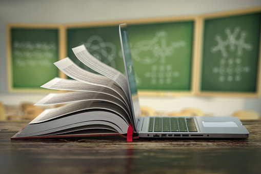 E-learning educación en línea o concepto de enciclopedia en Internet. Abra la compilación de computadoras portátiles y libros en un aula. photo